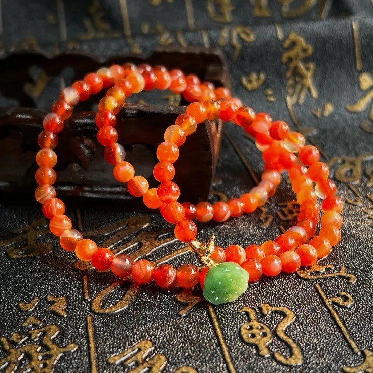 Crimson Ember Elixir bangle bracelet with vibrant red charm, close-up view.