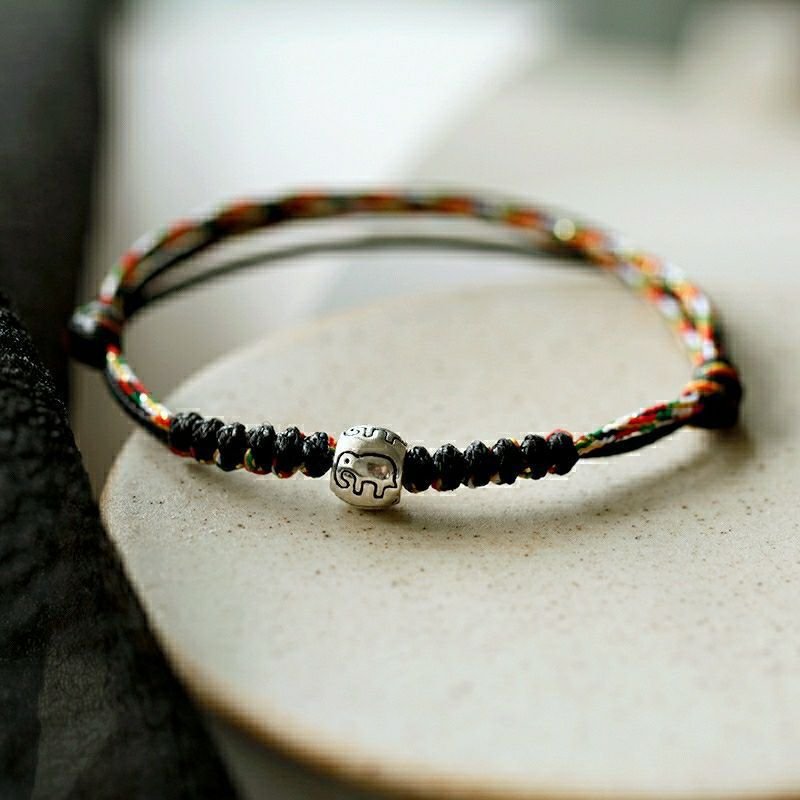 Golden red string evil eye bracelet with metallic charm, artisan jewelry.