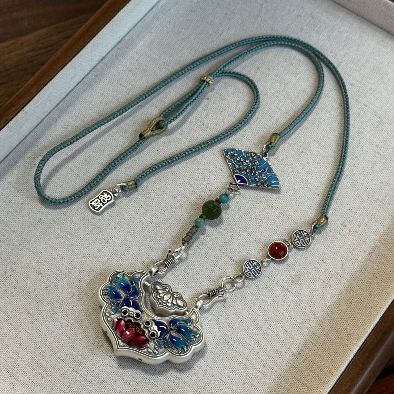Silver scale necklace with artisan-crafted balance charm, gold and silver tones.