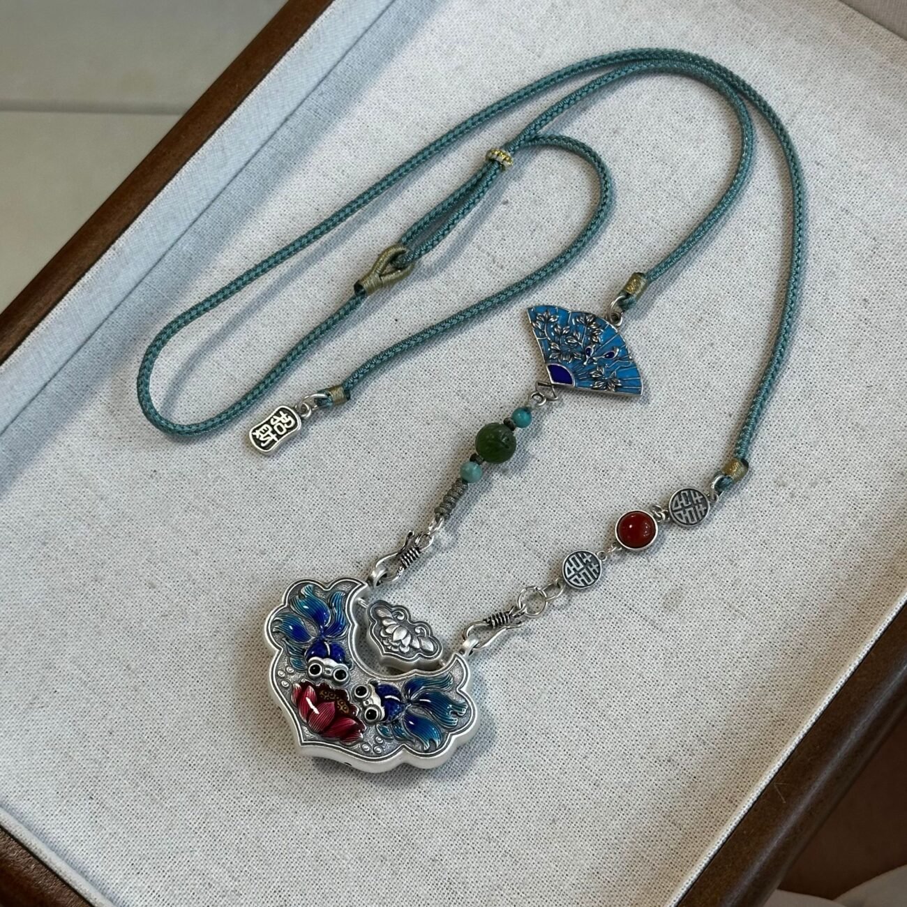 Silver scale necklace with artisan-crafted balance charm, gold and silver tones.