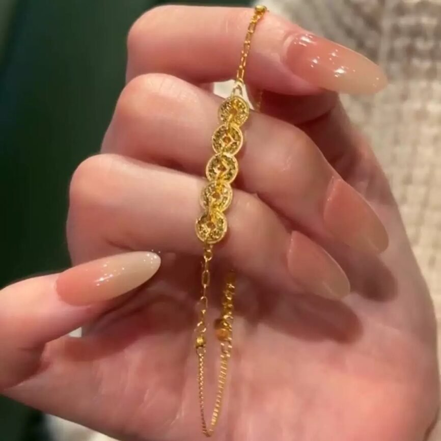 Golden Scale Ascendant Amulet charm on a gold bangle bracelet.