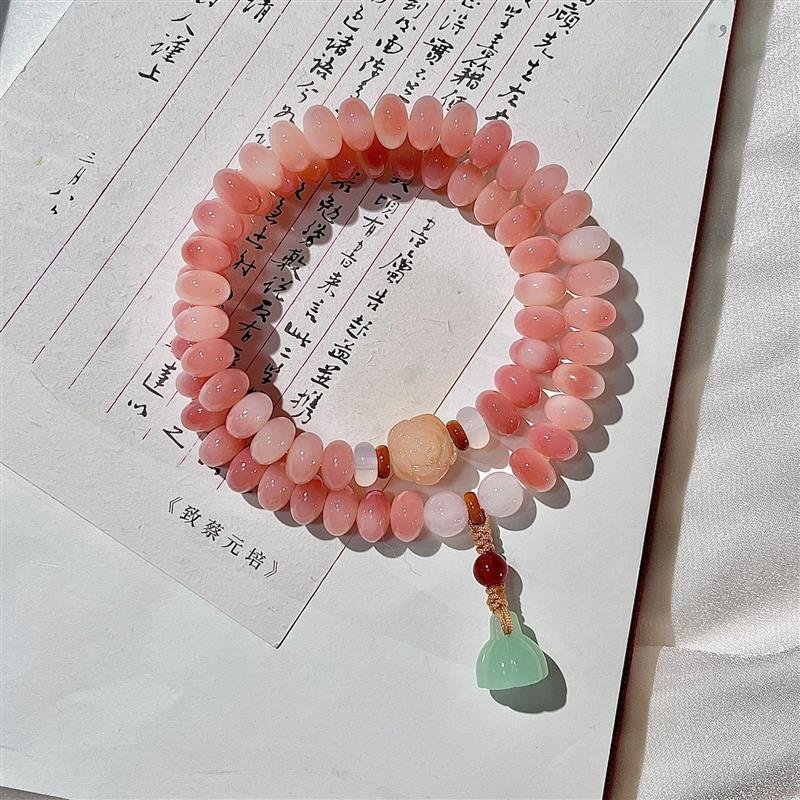 Peachwood mala beads with charm for wealth and harmony.